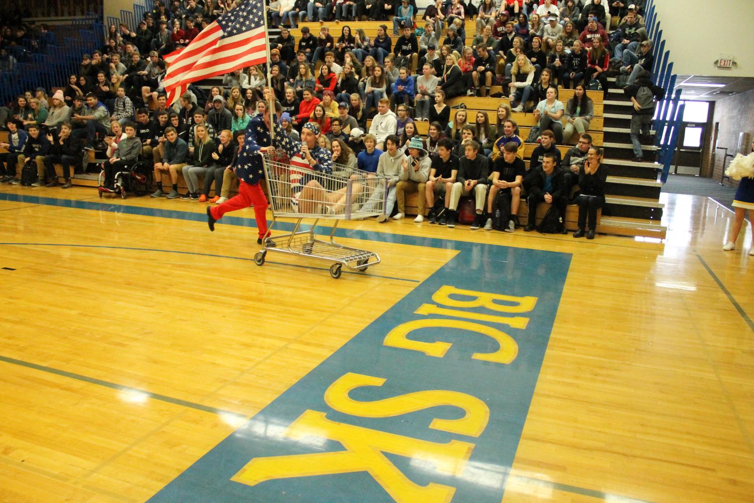 Student body presidents enter using a shopping cart with a United States Flag and dressed in all American Flag outfits.