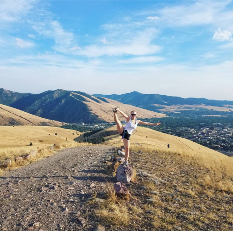 Girl does a Y scale on top of a mountain.