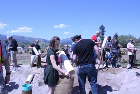 A student pulls out a tube from a sand bag as another watches.