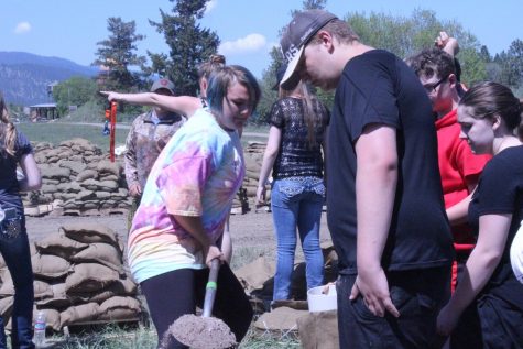 Student Nya fills up a sandbag as another watches, waiting to help.