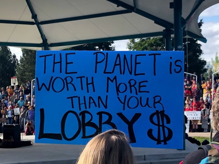 blue handmade sign reading, "The planet is worth more that your Lobby $"