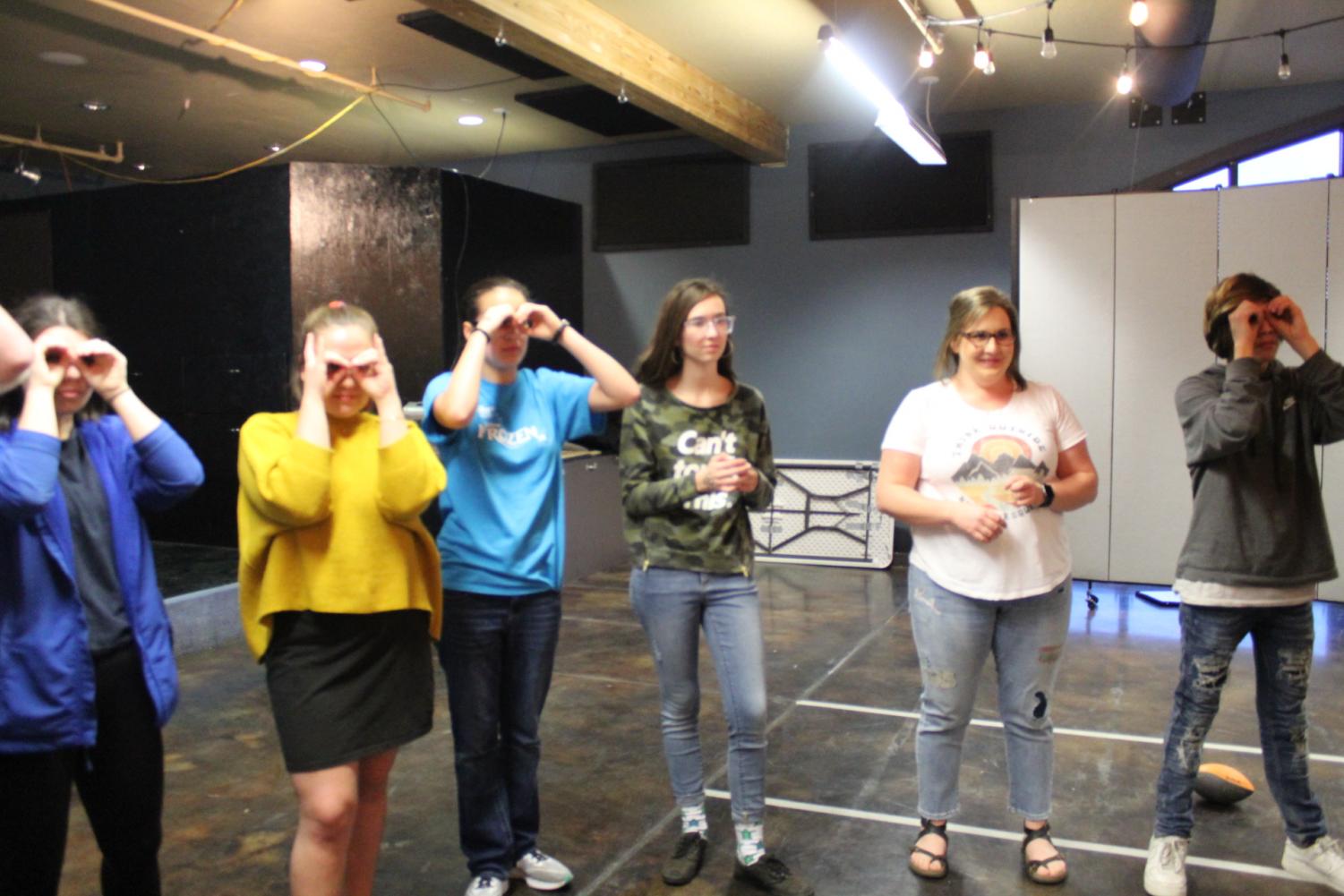 students standing in a rowmaking goggles with their hands