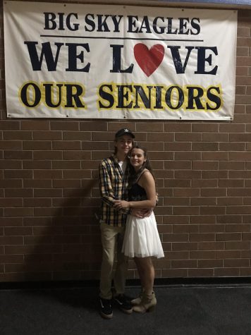 young man woman pose under a banner reading We love our seniors